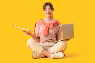 Canvas Print - Teenage girl with laptop and papers meditating on yellow background