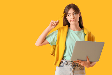 Canvas Print - Thoughtful teenage girl with laptop working online on yellow background