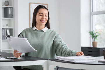 Wall Mural - Young businesswoman working on report at table in office