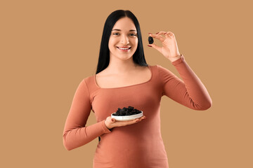 Wall Mural - Young pregnant woman with dried prunes on beige background