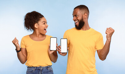 Wall Mural - excited over this new mobile app. overjoyed african american couple holding smartphones with mockup 