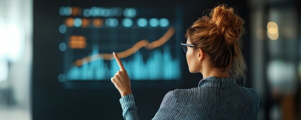 Wall Mural - young business woman pointing at growth curve displayed on digital screen in corporate office settin