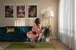 © Milles Studio/Stocksy - Focused pregnant woman doing squats at home