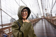 © Alvaro Lavin/Stocksy - Happy tourist laughing under the rain on Brooklyn Bridge