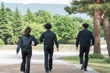 Canvas Print - 公園を歩く造園業・土木業の作業着姿の男女の作業員の後ろ姿
