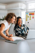 © Alvaro Lavin/Stocksy - Two businesswomen collaborating on laptop in coworking space
