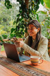 © Carlos Gonzales/Stocksy - Happy woman texting in her phone while working in laptop