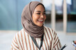 © Jovo Jovanovic/Stocksy - Closeup of cheerful young professional wearing hijab looking away