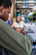 © Jovo Jovanovic/Stocksy - Afro man using smartphone while sitting with colleague at cafe