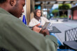 © Jovo Jovanovic/Stocksy - Man using smartphone while sitting with colleague at outdoor cafe