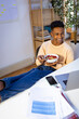 © Jimena Roquero/Stocksy - Young man eating healthy snack while having video call on laptop