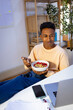© Jimena Roquero/Stocksy - Young man eating healthy snack while watching laptop