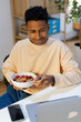 © Jimena Roquero/Stocksy - Young man looking at computer while having healthy breakfast