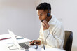© Jimena Roquero/Stocksy - Young man in office working on laptop using headset. Copy space