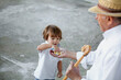 © Nasos Zovoilis/Stocksy - Child interacts with elder while sharing candy outdoors