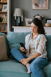 © Mihajlo Ckovric/Stocksy - Woman Relaxing on Couch Browsing Smartphone in Cozy Home Environment