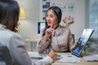 © amnaj - Asian businesswomen discussing marketing strategy showing charts and graphs on clipboard at office desk