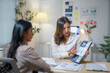 © amnaj - Asian businesswomen discussing and analyzing financial charts at office desk