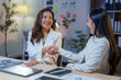 © amnaj - Two happy asian businesswomen shaking hands after closing a deal at night