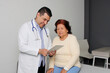 © Arlette - Elderly 80-year-old Latin woman visits the dark-skinned geriatric specialist medical doctor to check her health, they greet each other, laugh and hug