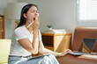 © Phimwilai - Young asian woman yawning while working remotely from home, displaying signs of fatigue and sleepiness caused by overwork or a restless night’s sleep
