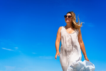 Wall Mural - Portrait of beautiful middle aged woman walking against background of blue sky in summertime. 