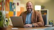 © Berkah - Professional man in brown jacket using a laptop at his desk in a bright office setting
