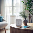 © LIDIIA - Smart Home Hub. Wireless control hub on wooden side table with smartphone and decorative vase in bright modern living space.
