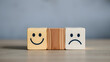 © Tark - Mental health and emotional state concept, Smile face in bright side and sad face in dark side on wooden block cube for positive mindset selection. Generative AI