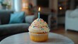 © Mark - A solitary lit candle adorns a colorful birthday cupcake amid festive balloons and streamers within a modern living room, celebrating a special day filled with joy and happiness
