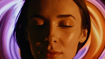 Leinwandbilder - a moody close-up of a woman’s face, framed by swirling orange and purple tones.