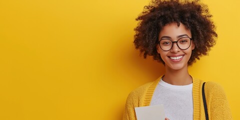 Wall Mural - A woman with curly hair and glasses is smiling and holding a piece of paper. Concept of warmth and friendliness, as the woman is happy and comfortable in her surroundings