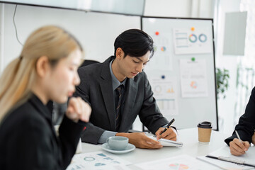 Wall Mural - focused business professional taking notes during a financial meeting in a modern office setting.