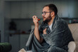 © Ljustina - Sick man using inhaler at home wrapped in blanket