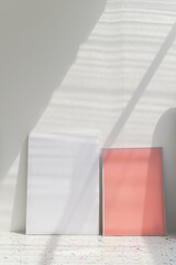 Aufkleber - Minimalist art display with white and coral canvases in soft light