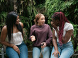 © Martin Stock Studio - Three young women sharing funny secrets in a park