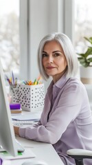 Aufkleber - Middle-aged woman working with focus at a modern desk in a bright office