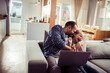 © Geber86 - Father and daughter using a laptop while sitting on the couch in the living room