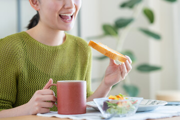 朝食で食パンを食べる若い女性