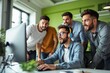 © Pixels Hunter - Group of young men excitedly looking at a computer screen in a modern office with green interior background.