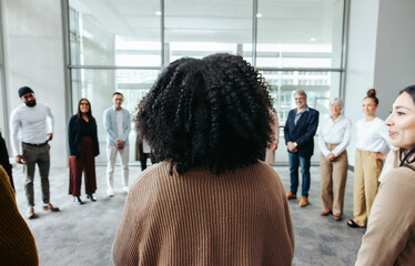 Wall Mural - businesswoman presenting at a conference with colleagues standing in a circle