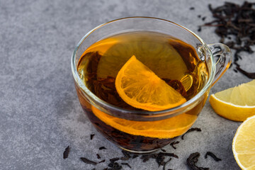 Wall Mural - Glass cup of black tea with lemon on gray background.