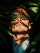 © THINGDSGN - confident businessman in sunglasses surrounded by tropical leaves, dramatic sunlight and shadows