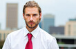 © Minerva Studio - Serious businessman posing in front of city skyline wearing white shirt and red tie