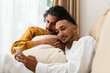 © Alberto Midnight/Stocksy - Gay couple resting on the sofa at home, looking at the phone together