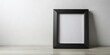 © VisualVault - Blank black picture frame on a shelf against a wall