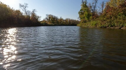 Wall Mural - Point of view from front of canoe while paddling along a river in autumn surrounded by colorful trees
