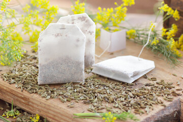 Wall Mural - Fennel seed tea bags on wooden kitchen background with fresh flowers nearby, copy space, natural medicine, drink for breast milk production, sleep and stress care concept