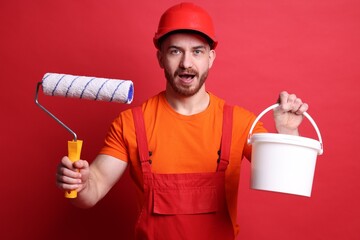 Wall Mural - Emotional painter with roller and bucket of paint on red background