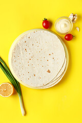 Canvas Print - Board with thin lavash, tomatoes and sauce on yellow background